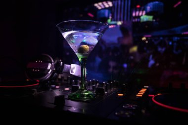 Martini gece kulübünde dj denetleyicisinde içinde zeytin ile bardak. Club içki müzik parti disko ışıkları ile gece kulübünde DJ konsolu.