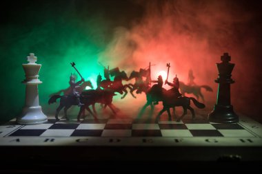 Süvari ve satranç tahtası üzerinde piyade ile ortaçağ savaş sahnesi. Satranç oyununu kavramı iş fikirleri ve rekabet ve strateji fikirler duman ve sis karanlık bir arka plan üzerinde satranç figürleri.