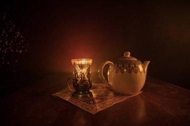 Geleneksel glasse ve ışıklar ve duman siyah zemin üzerine pot Doğu tea. Doğu çay kavramı. Armudu geleneksel Azerbaycan/Türkiye Kupası. Seçici odak. Bardak çay