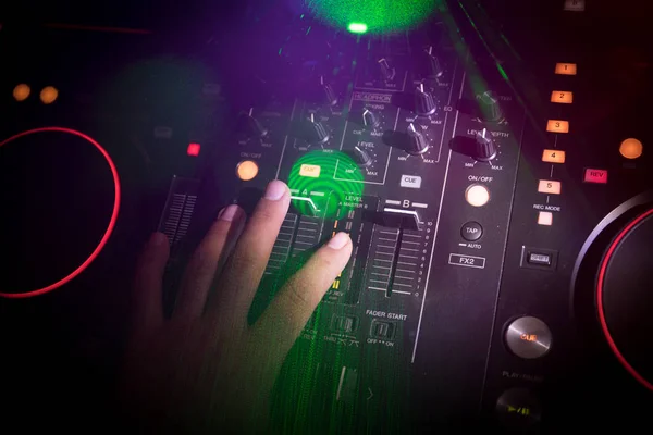 stock image In selective focus of Pro dj controller.The DJ console deejay mixing desk at music party in nightclub with colored disco lights. Close up view
