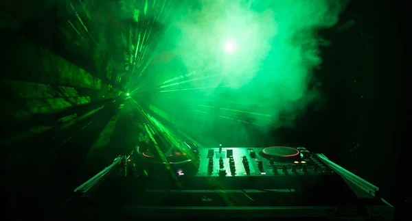 stock image DJ Spinning, Mixing, and Scratching in a Night Club, Hands of dj tweak various track controls on dj's deck, strobe lights and fog, or Dj mixes the track in the nightclub at party. Selective focus