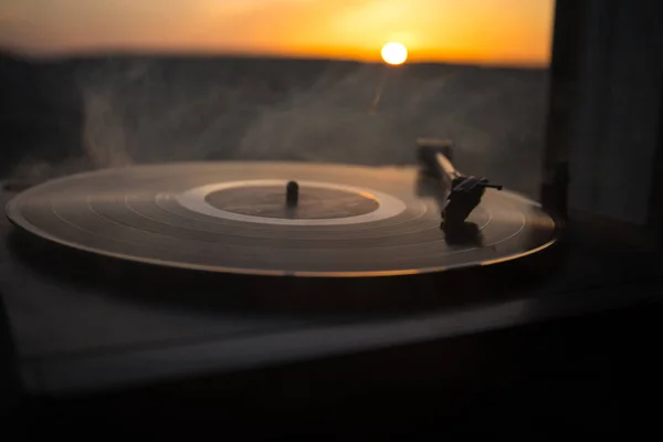 山に沈む夕日の背景にターン テーブル ビニール レコード プレーヤー ミックス 音楽を再生するためのサウンド テクノロジー 黒のビニール レコード — ストック写真