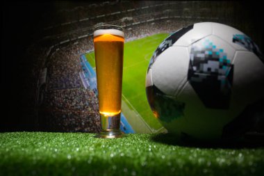 Bakü, Azerbaycan - 23 Haziran 2018: Resmi Rusya 2018 Dünya Kupası futbol topu Adidas Telstar 18 ve tek bira cam oynama bulanık manzaralı koyu tonda sisli arka plan, çimenlerin üzerinde oyun