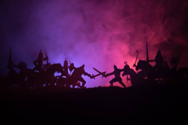 Medieval battle scene with cavalry and infantry. Silhouettes of figures as separate objects, fight between warriors on dark toned foggy background. Night scene. Selective focus clipart