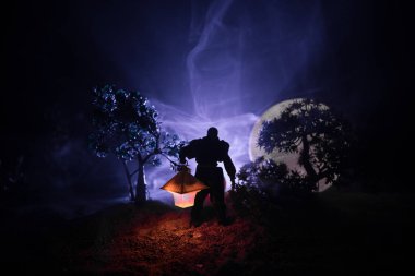 Yağmurluk ile onun el kavramı içinde parlayan fener karanlık ormanın gelen adam. Lamba korku katille silüeti. Dekorasyon