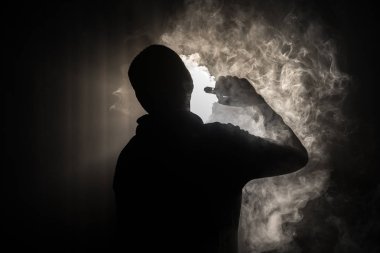 Bir mod tutarak Vaping adam. Buhar bulutu. karanlık sisli bulutlar duman arka plan tonda. Vaping elektronik sigara duman bir sürü ile. Vape kavramı. Seçici odak