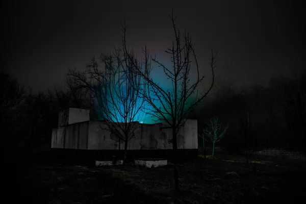 Old house with a Ghost in the forest at night or Abandoned Haunted Horror House in fog. Old mystic building in dead tree forest. Creepy house in the middle of a dark forest. Surreal lights