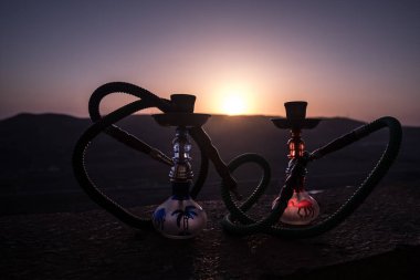 Nargile, geleneksel Arapça harcamak, doğrudan günbatımı güneş ışığı, açık fotoğraf. Dağ arka plan veya nargile günbatımı arka plan üzerinde siluetleri. Açık. Seçici odak