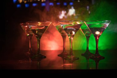 Ünlü kokteyl Martini, birkaç bardak koyu tonda sisli arka plan ve disko ışıkları ile bir barda vurdu. Club içki kavramı. Seçici odak