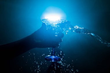 Martini kokteyl cam el koyu tonda dumanlı arka plan veya renkli kokteyl cam su sıçramalarına ve zeytin sıçramasına. Parti club eğlence. Karışık ışık. Seçici odak