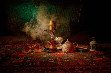Nargile kömürü nargile kupa Arap iç de buhar bulutları yapma. Şark süsleme halı Doğu çay töreni üzerinde. Şık oryantal shisha içinde karanlık arka ışık ile. Seçici odak