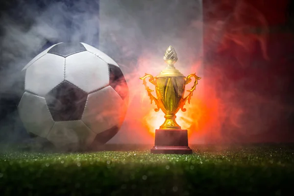 France flag, golden champion\'s cup and soccer ball on grass.Concept sport. Selective focus