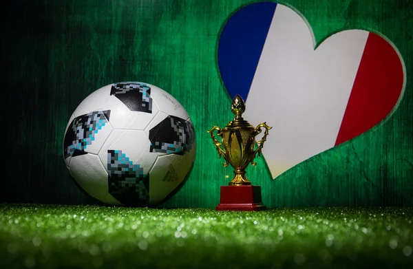 Bakü, Azerbaycan - 13 Temmuz 2018: Yaratıcı kavramı. Resmi Rusya 2018 Dünya Kupası futbol topu Adidas Telstar 18 ve şampiyon bir fincan yeşil çimenlerin üzerinde. Destek Fransa takım kavramı. Seçici odak