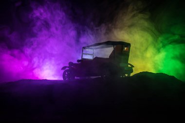 Eski eski model araba içinde karanlık sisli silüeti düşük ışıkta parlayan ışıklar ile arka plan tonda. Seçici odak