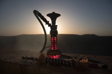 Nargile, geleneksel Arapça harcamak, doğrudan günbatımı güneş ışığı, açık fotoğraf. Dağ arka plan veya nargile günbatımı arka plan üzerinde siluetleri. Açık. Seçici odak
