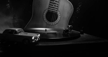 Arka plan ateş portakal duman ile oyuncu ve akustik gitarda oynamak vintage vinil kaydı. Blues kavramı. Oyuncak araba ile. Seçici odak
