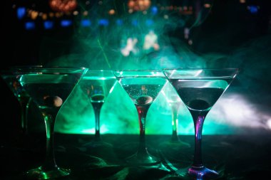 Ünlü kokteyl Martini, birkaç bardak koyu tonda sisli arka plan ve disko ışıkları ile bir barda vurdu. Club içki kavramı. Seçici odak