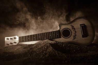 Müzik konsepti. Akustik gitar ile kopya alanı dumanla ışık demeti altında karanlık bir arka plan üzerinde izole. Gitar telleri, yakın çekim. Seçici odak.
