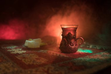Cam bir halı ile ışık ve duman koyu arka plan üzerinde Doğu snacks ile Arap tea. Doğu çay kavramı. Boş alanı. Seçici odak.