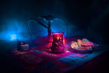 Nargile kömürü nargile kupa Arap iç de buhar bulutları yapma. Şark süsleme halı Doğu çay töreni üzerinde. Şık oryantal shisha içinde karanlık arka ışık ile. Seçici odak