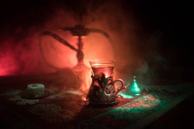 Nargile kömürü nargile kupa Arap iç de buhar bulutları yapma. Şark süsleme halı Doğu çay töreni üzerinde. Şık oryantal shisha içinde karanlık arka ışık ile. Seçici odak