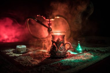 Nargile kömürü nargile kupa Arap iç de buhar bulutları yapma. Şark süsleme halı Doğu çay töreni üzerinde. Şık oryantal shisha içinde karanlık arka ışık ile. Seçici odak