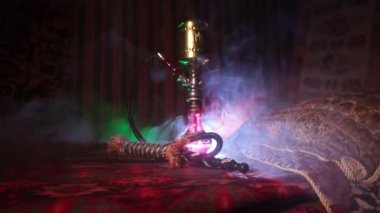 Nargile kömürü nargile kupa Arap iç de buhar bulutları yapma. Şark süsleme halı üzerinde. Şık oryantal shisha içinde karanlık arka ışık ile. Kaymak vurdu. Boş alan