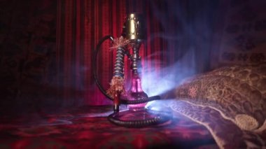 Nargile kömürü nargile kupa Arap iç de buhar bulutları yapma. Şark süsleme halı üzerinde. Şık oryantal shisha içinde karanlık arka ışık ile. Kaymak vurdu. Boş alan