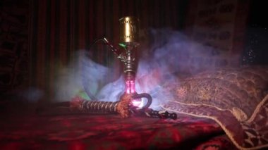 Nargile kömürü nargile kupa Arap iç de buhar bulutları yapma. Şark süsleme halı üzerinde. Şık oryantal shisha içinde karanlık arka ışık ile. Kaymak vurdu. Boş alan