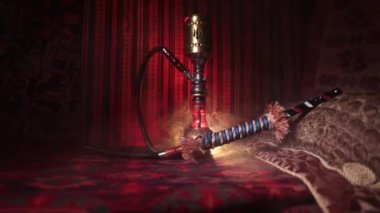 Nargile kömürü nargile kupa Arap iç de buhar bulutları yapma. Şark süsleme halı üzerinde. Şık oryantal shisha içinde karanlık arka ışık ile. Kaymak vurdu. Boş alan