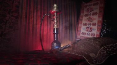 Nargile kömürü nargile kupa Arap iç de buhar bulutları yapma. Şark süsleme halı üzerinde. Şık oryantal shisha içinde karanlık arka ışık ile. Kaymak vurdu. Boş alan