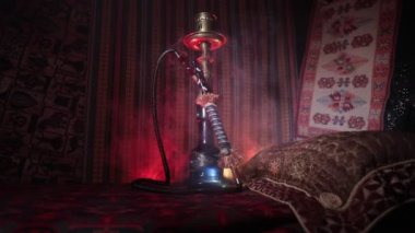 Nargile kömürü nargile kupa Arap iç de buhar bulutları yapma. Şark süsleme halı üzerinde. Şık oryantal shisha içinde karanlık arka ışık ile. Kaymak vurdu. Boş alan