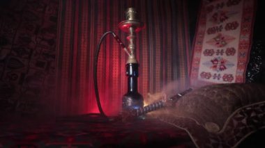 Nargile kömürü nargile kupa Arap iç de buhar bulutları yapma. Şark süsleme halı üzerinde. Şık oryantal shisha içinde karanlık arka ışık ile. Kaymak vurdu. Boş alan