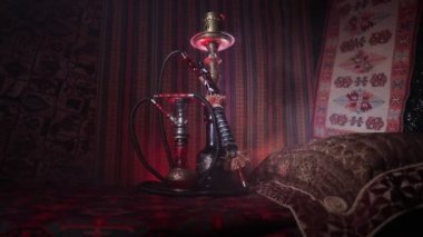 Nargile kömürü nargile kupa Arap iç de buhar bulutları yapma. Şark süsleme halı üzerinde. Şık oryantal shisha içinde karanlık arka ışık ile. Kaymak vurdu. Boş alan
