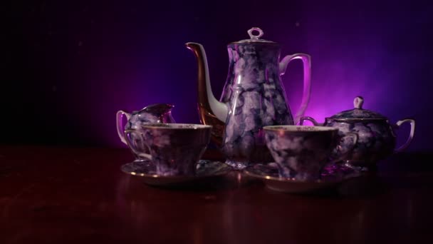 咖啡或茶道的概念主题 老式的陶瓷茶或咖啡壶与杯壶和糖杯在黑暗色调背景与光和烟雾 文本的空白 滑块射击 — 图库视频影像