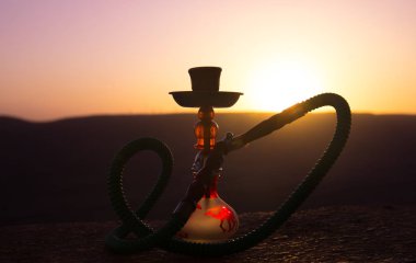 Nargile, geleneksel Arapça harcamak, doğrudan günbatımı güneş ışığı, açık fotoğraf. Dağ arka plan veya nargile günbatımı arka plan üzerinde siluetleri. Açık. Seçici odak