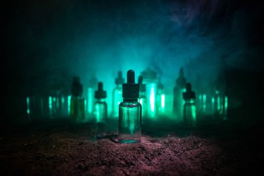 Vape konsepti. Karanlık arka planda duman bulutları ve tüp sıvısı şişeleri. Işık efektleri. Arka plan, vape reklamı ya da vape arkaplan olarak kullanışlı. Seçici odak