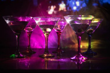 Ünlü kokteyl Martini, birkaç bardak koyu tonda sisli arka plan ve disko ışıkları ile bir barda vurdu. Club içki kavramı. Seçici odak