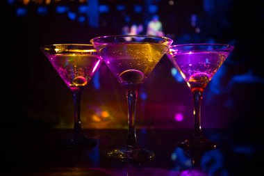 Ünlü kokteyl Martini, birkaç bardak koyu tonda sisli arka plan ve disko ışıkları ile bir barda vurdu. Club içki kavramı. Seçici odak