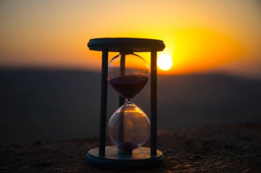 Kum saati geçen zaman atlamalı bulutlar. Bir kum saati önünde parlak mavi gökyüzü ile kabarık beyaz bulutlar geçiyor. Zaman kavramı. Günbatımı zamanı. Seçici odak