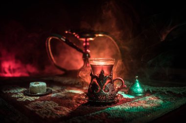 Nargile kömürü nargile kupa Arap iç de buhar bulutları yapma. Şark süsleme halı Doğu çay töreni üzerinde. Şık oryantal shisha içinde karanlık arka ışık ile. Seçici odak