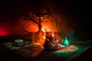 Nargile kömürü nargile kupa Arap iç de buhar bulutları yapma. Şark süsleme halı Doğu çay töreni üzerinde. Şık oryantal shisha içinde karanlık arka ışık ile. Seçici odak