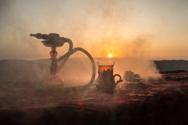 Nargile kömürü nargile kupa çöl de buhar bulutları açık yapma. Şark süsleme halı Doğu çay töreni üzerinde. Şık oryantal shisha günbatımı arka plan üzerinde. Seçici odak
