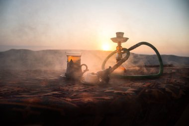Nargile kömürü nargile kupa çöl de buhar bulutları açık yapma. Şark süsleme halı Doğu çay töreni üzerinde. Şık oryantal shisha günbatımı arka plan üzerinde. Seçici odak
