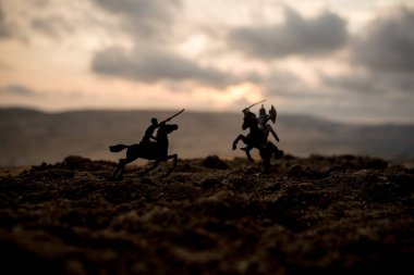 Süvari ve piyade ile ortaçağ savaş sahnesi. Siluetleri şekiller ayrı nesneler olarak mücadele günbatımı sisli arka plan savaşçılar arasında. Seçici odak