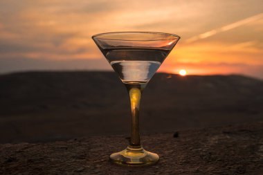 Dağları ile günbatımı arka plan karşı bir bardak Martini. İçki günbatımı zaman kulübü. Seçici odak