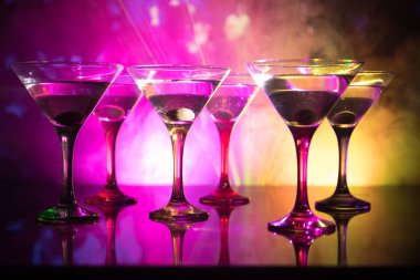 Ünlü kokteyl Martini, birkaç bardak koyu tonda sisli arka plan ve disko ışıkları ile bir barda vurdu. Club içki kavramı. Seçici odak