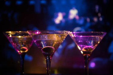 Ünlü kokteyl Martini, birkaç bardak koyu tonda sisli arka plan ve disko ışıkları ile bir barda vurdu. Club içki kavramı. Seçici odak