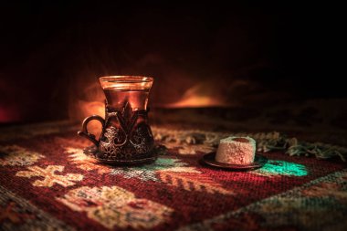 Cam bir halı ile ışık ve duman koyu arka plan üzerinde Doğu snacks ile Arap tea. Doğu çay kavramı. Boş alanı. Seçici odak.