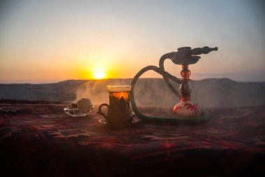 Nargile kömürü nargile kupa çöl de buhar bulutları açık yapma. Şark süsleme halı Doğu çay töreni üzerinde. Şık oryantal shisha günbatımı arka plan üzerinde. Seçici odak